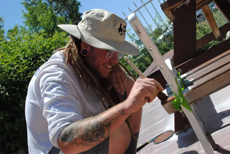 A Kind Home Painting volunteer refinishing a chair at an Extreme Community Makeover project
